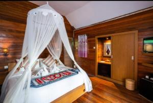 a bedroom with a white bed with a canopy at Bali Nusa Cottage in Nusa Lembongan