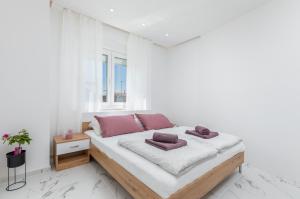 biała sypialnia z łóżkiem i oknem w obiekcie Apartman Knezevic A w Fažanie