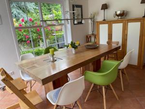 a dining room with a wooden table and green chairs at "Haus ViDa" in Kellenhusen