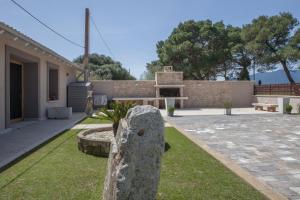 a garden with a stone monument in front of a house at Relais Borgo Camisa in Castiadas