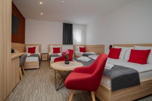 a hotel room with two beds and a red chair at Maestro - Rooms & Resturant in Vukovar