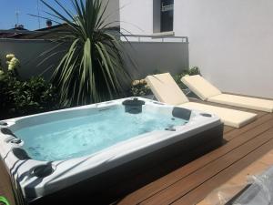 a hot tub sitting on a deck with two chairs at Ninfea Wellness & Spa Residence in Caorle
