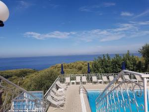 a swimming pool with chairs and the ocean in the background at Hotel Dania in Sorrento