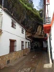 an alley with a white building next to a mountain at CASA ENROCADA in Setenil