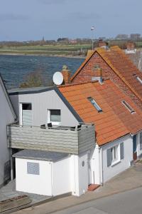 um grupo de edifícios com telhados laranja junto à água em Fischerhaus Lemkenhafen em Lemkenhafen auf Fehmarn