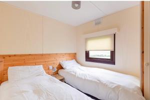 two beds in a room with a window at Lodge Cabin with Fabulous Views - Farm Holiday in Stranraer