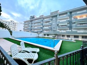 a swimming pool with two lawn chairs and a building at Sunny Escape in El Campello in El Campello