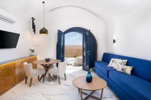 a living room with a blue couch and tables at Amera Suites in Fira