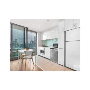 a kitchen with white appliances and a table with a view at Lovely apartment in Melbourne