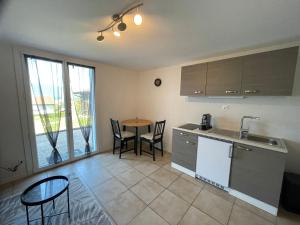 a kitchen with a sink and a table with chairs at Studio Terrasse Vue Lac Entrée indépendante in Font