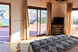 a bedroom with a bed and a large window at Villa sur le lac Bin el ouidane in Aït Irizane