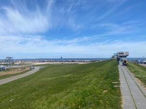 a grassy field with people walking down a sidewalk at Meeresbrise 2 in Norden