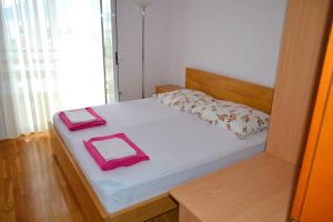 ein kleines Schlafzimmer mit einem Bett mit rosa Gegenständen darauf in der Unterkunft Tivat Apartments in Tivat