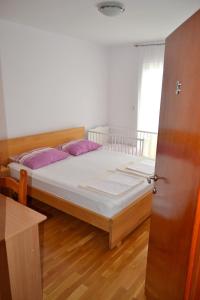 ein Schlafzimmer mit einem Bett mit lila Kissen darauf in der Unterkunft Tivat Apartments in Tivat