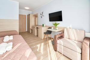 a hotel room with a couch and a desk and a television at Villa Polna in Grzybowo