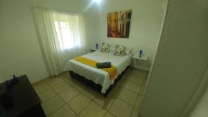 Four Seasons Self-Catering Guest House في غراسكوب: غرفة نوم بسرير وبطانية صفراء
