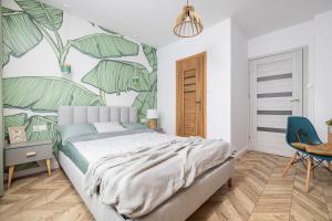 a bedroom with a bed with a mural of leaves at Apartament SUNBEAM Władysławowo Chłapowo in Władysławowo