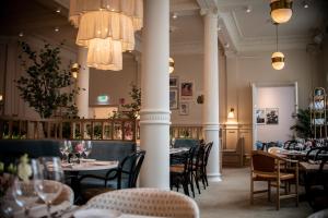 a restaurant with tables and chairs and chandeliers at Elite Hotel Mårtenson in Halmstad