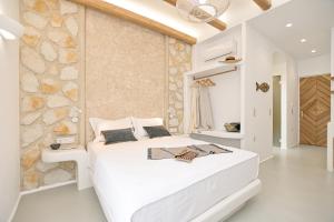 a white bedroom with a large white bed and a stone wall at Flèria Seaview Suites in Naxos Chora
