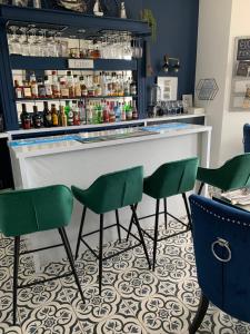 um bar com cadeiras verdes em frente a um balcão em Lazy Waves Boutique B&B em Newquay