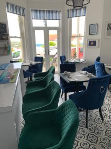um restaurante com cadeiras verdes, mesas e janelas em Lazy Waves Boutique B&B em Newquay