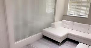 a white couch in a room with a window at Luxurious high spec 1 bedroom apartment in London in Eltham
