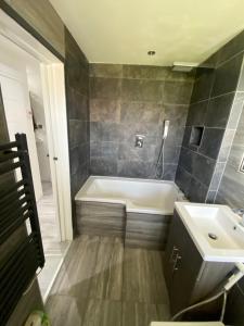 a bathroom with a bath tub and a sink at Luxurious high spec 1 bedroom apartment in London in Eltham
