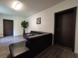 a living room with a black leather couch and a table at Ferienwohnung am Wiedenberg in Arnsberg