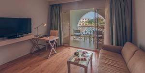 a living room with a couch and a television and a table at Old Palace Resort Sahl Hasheesh in Hurghada