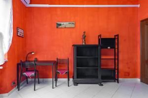einen Tisch und Stühle in einem Zimmer mit orangefarbener Wand in der Unterkunft Casa Metro Lingotto in Turin