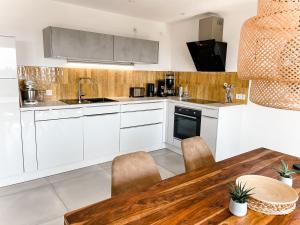 a kitchen with white cabinets and a wooden table at TANTE IDA‘S in Lindau-Bodolz