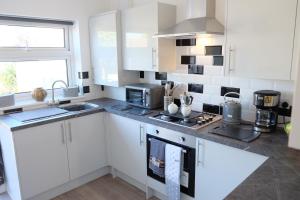 a kitchen with white cabinets and a sink at 18 Cheerful 2 bed bungalow, hot tub, gym, pool table in Prestatyn