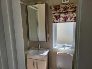 a bathroom with a sink and a window and a toilet at 2BR-Sleeps6-Fireplace-Parking-Patio-Seaside in Clacton-on-Sea
