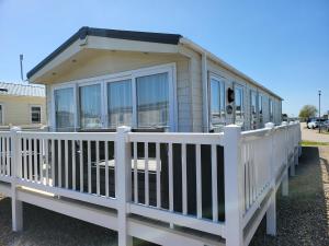 a mobile home with a white fence at 2BR-Sleeps6-Fireplace-Parking-Patio-Seaside in Clacton-on-Sea