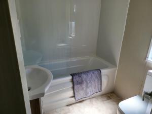 a bathroom with a sink and a tub and a toilet at 2BR-Sleeps6-Fireplace-Parking-Patio-Seaside in Clacton-on-Sea