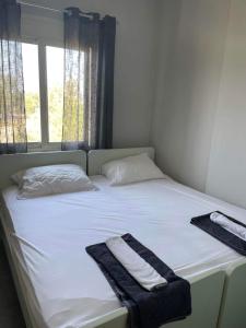 ein weißes Bett mit zwei Handtüchern und einem Fenster in der Unterkunft Riviera in Vlorë