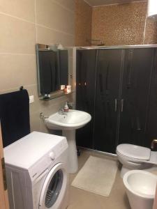 ein Badezimmer mit einer Waschmaschine, einem WC und einem Waschbecken in der Unterkunft Riviera in Vlorë