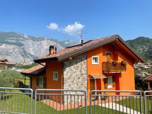ein orangefarbenes Haus mit Balkon und Bergen im Hintergrund in der Unterkunft Villetta Drena in Drena