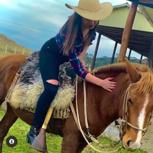 a young woman riding on the back of a horse at POUSADA FAZENDA PAIM in São José dos Ausentes