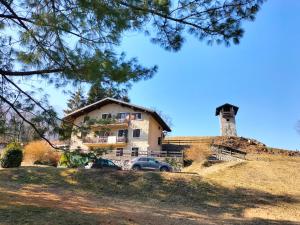 una casa en una colina con un coche aparcado delante en LA TORRETTA SUL LAGO di TENNO - RESIDENCE LA RUSTICA en Tenno