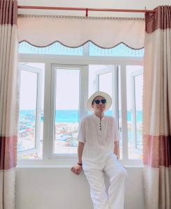 a man in a hat sitting in front of a window at Binh Yen Hotel in Ly Son