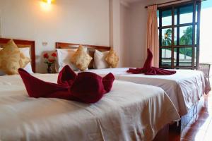 two beds in a room with red pillows on them at Bonny Hotel in Lamai