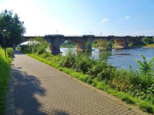 a path next to a river with a bridge in the background at Apartment Altstadt 2 in Pirna