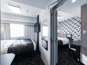 a hotel room with two beds and a desk at APA Hotel Shin Osaka Ekimae in Osaka