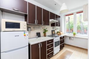 a kitchen with brown cabinets and a white refrigerator at SuperApart Dzielna 9a in Warsaw