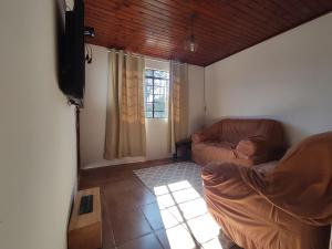 a living room with a couch and a flat screen tv at Casa com excelente localização in Campos do Jordão