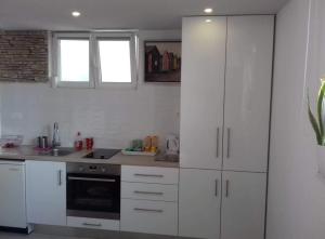 a white kitchen with white cabinets and a stove at Stone Guest House in Split