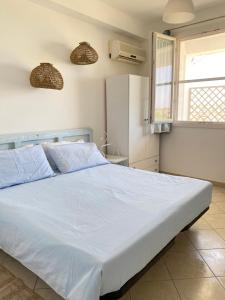 a bedroom with a large white bed and a window at Diga Rooms in Marzamemi
