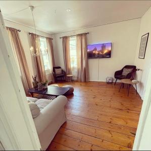 een woonkamer met een witte bank en houten vloeren bij Kristianstad Guest House in Kristianstad