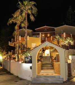 a building with an arch and palm trees at night at Heaven Apartments in Agia Marina Nea Kydonias